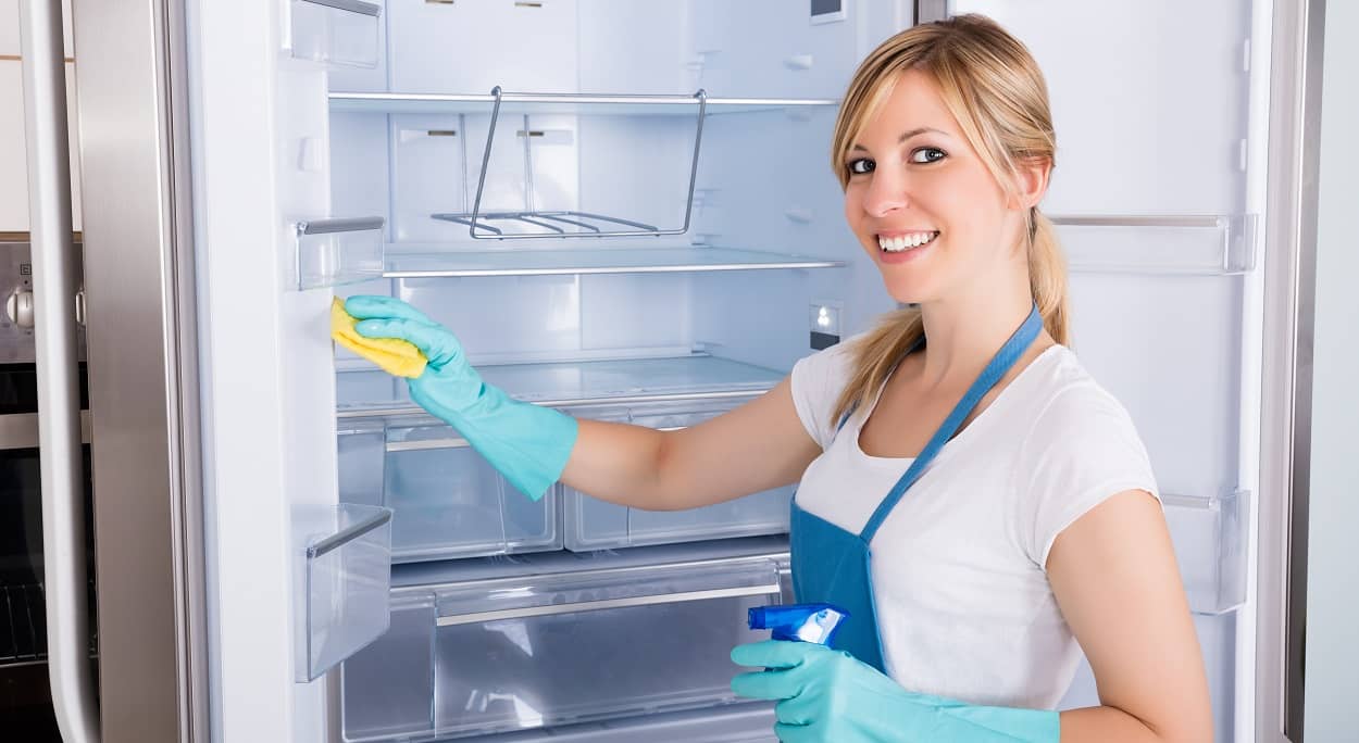 Junge Frau beim Kühlschrank reinigen